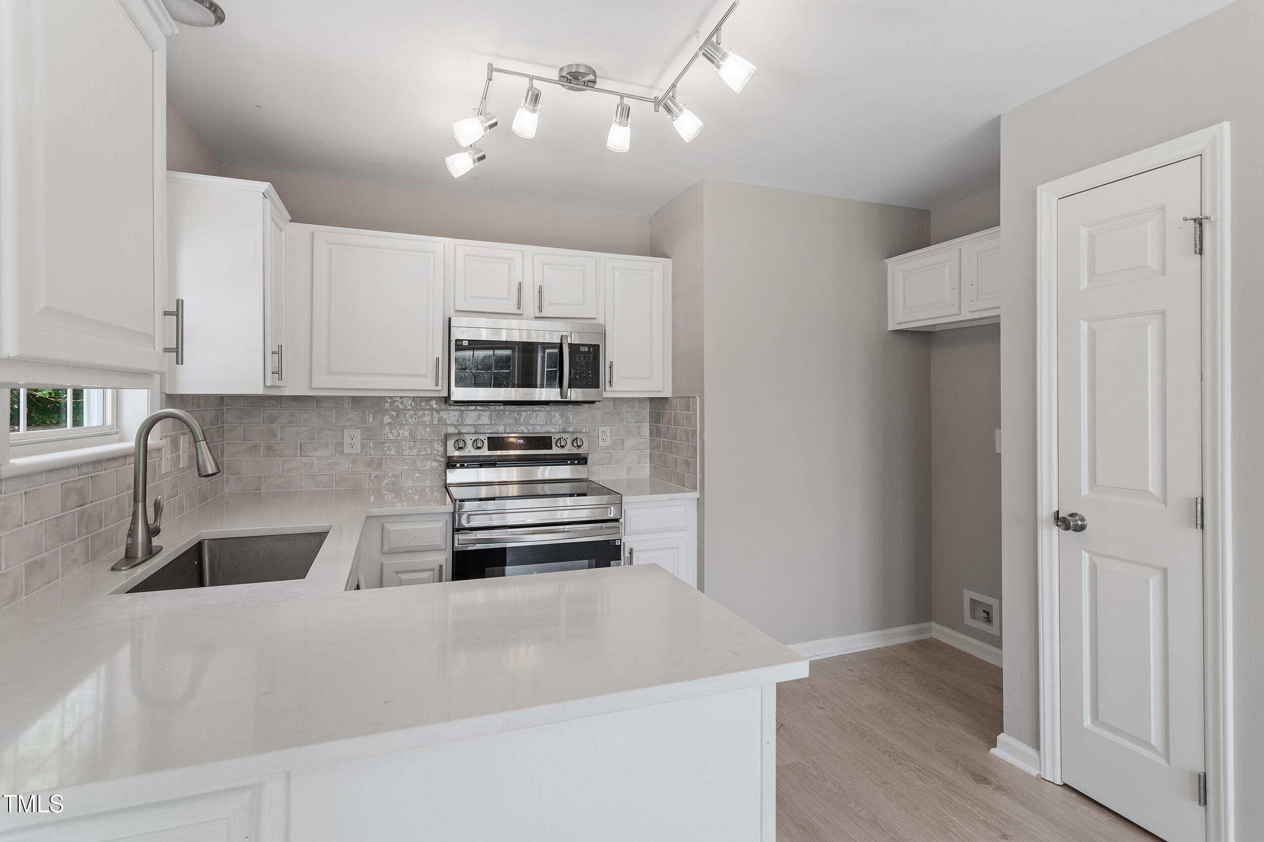 a kitchen with stainless steel appliances a stove a sink and white cabinets