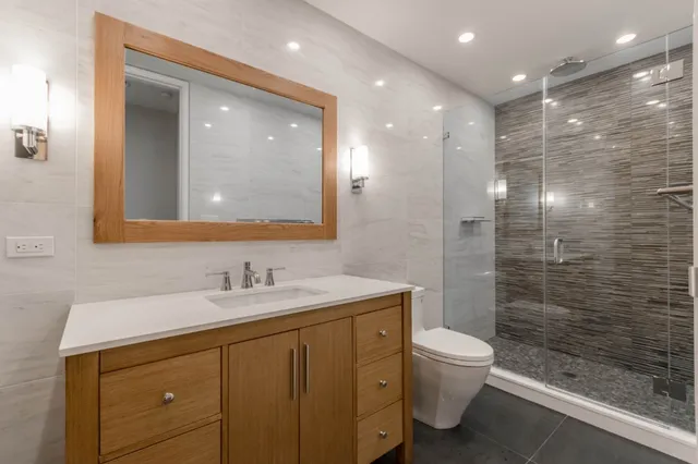 a bathroom with a sink a toilet a shower and a mirror