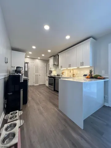 a open kitchen with kitchen island white cabinets and stainless steel appliances