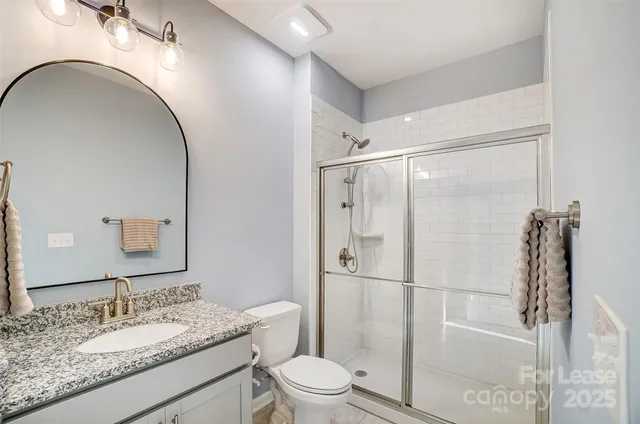 a bathroom with a granite countertop sink toilet mirror and shower