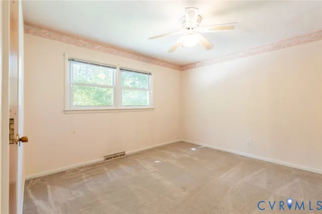 an empty room with windows and fan