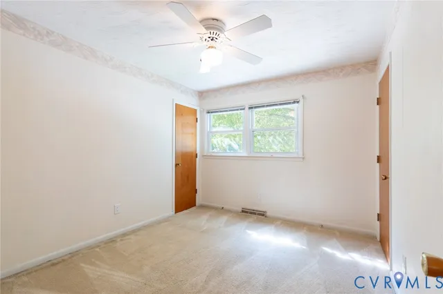 an empty room with windows and fan