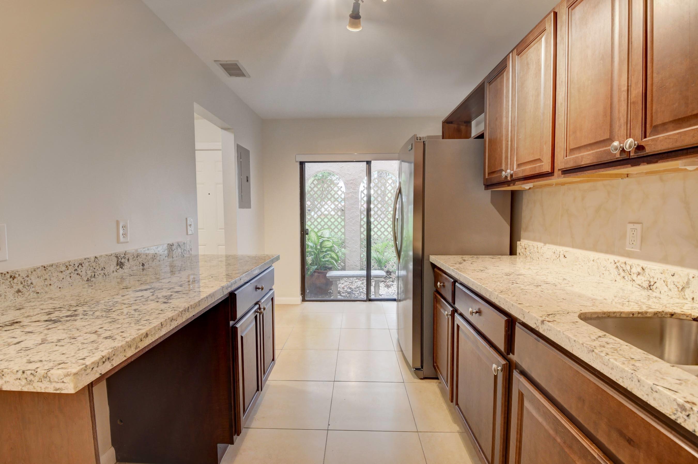 21748 Juego Circle, Unit 21E Boca Raton, FL 33433 - Photo 25 of 56 a kitchen with a sink stove and cabinets