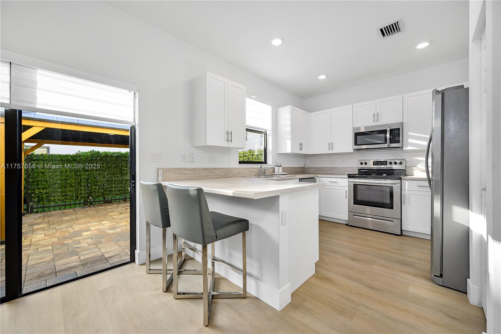 4671 Santa Cruz Way, Unit 4671 Davie, FL 33314 - Photo 11 of 20 a kitchen with stainless steel appliances granite countertop a stove a sink a microwave a refrigerator and white cabinets with wooden floor