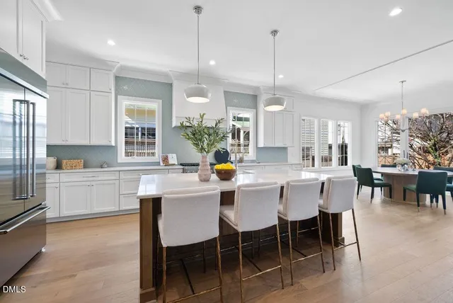 a kitchen with a dining table chairs wooden floor cabinets appliances and a window