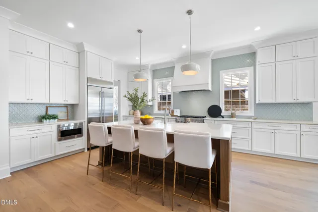 a kitchen with kitchen island a stove a counter top space a sink and cabinets