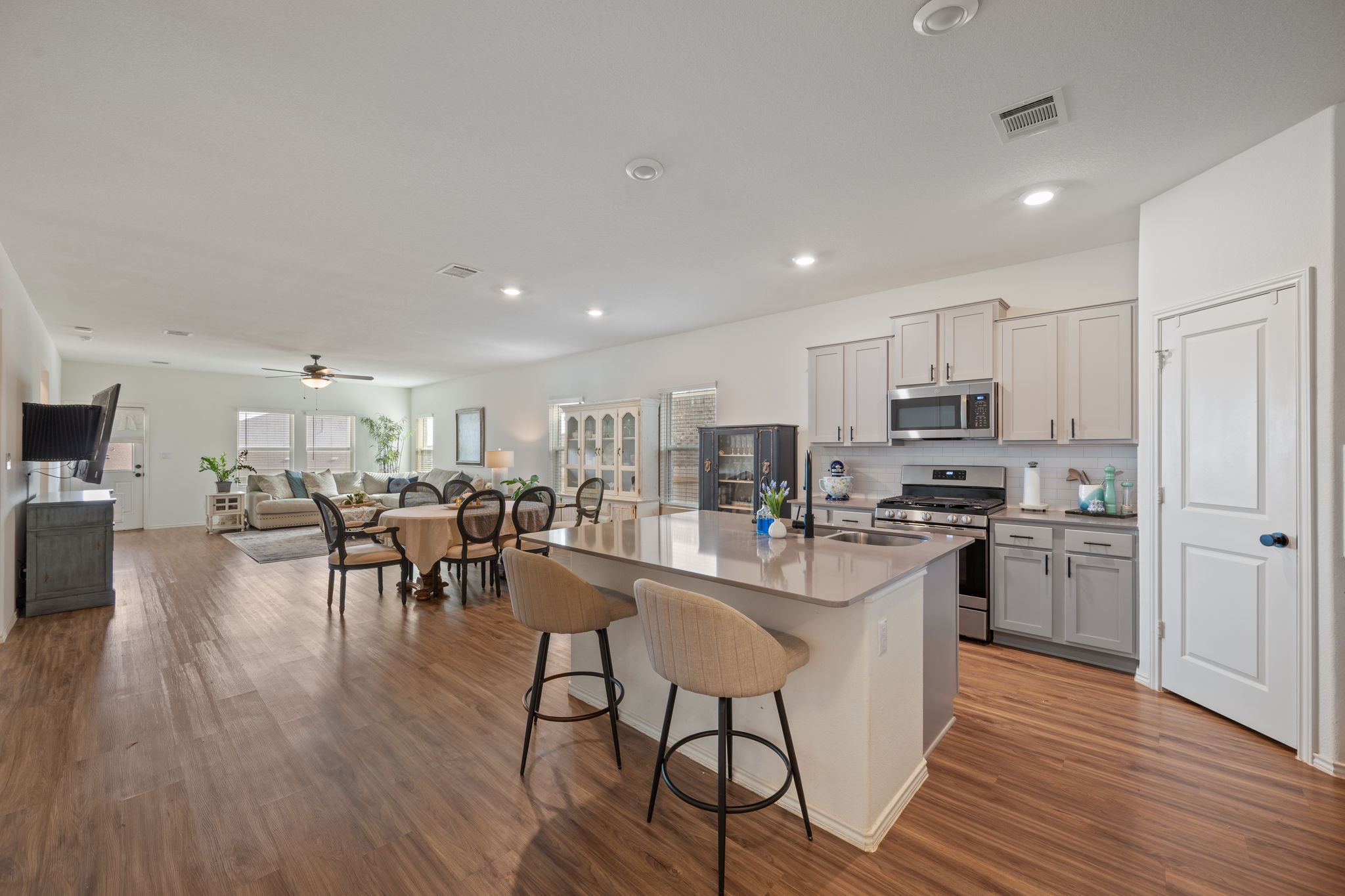 705 Mallow Road Leander, TX 78641 - Photo 6 of 29 a kitchen with stainless steel appliances kitchen island wooden floors and white cabinets