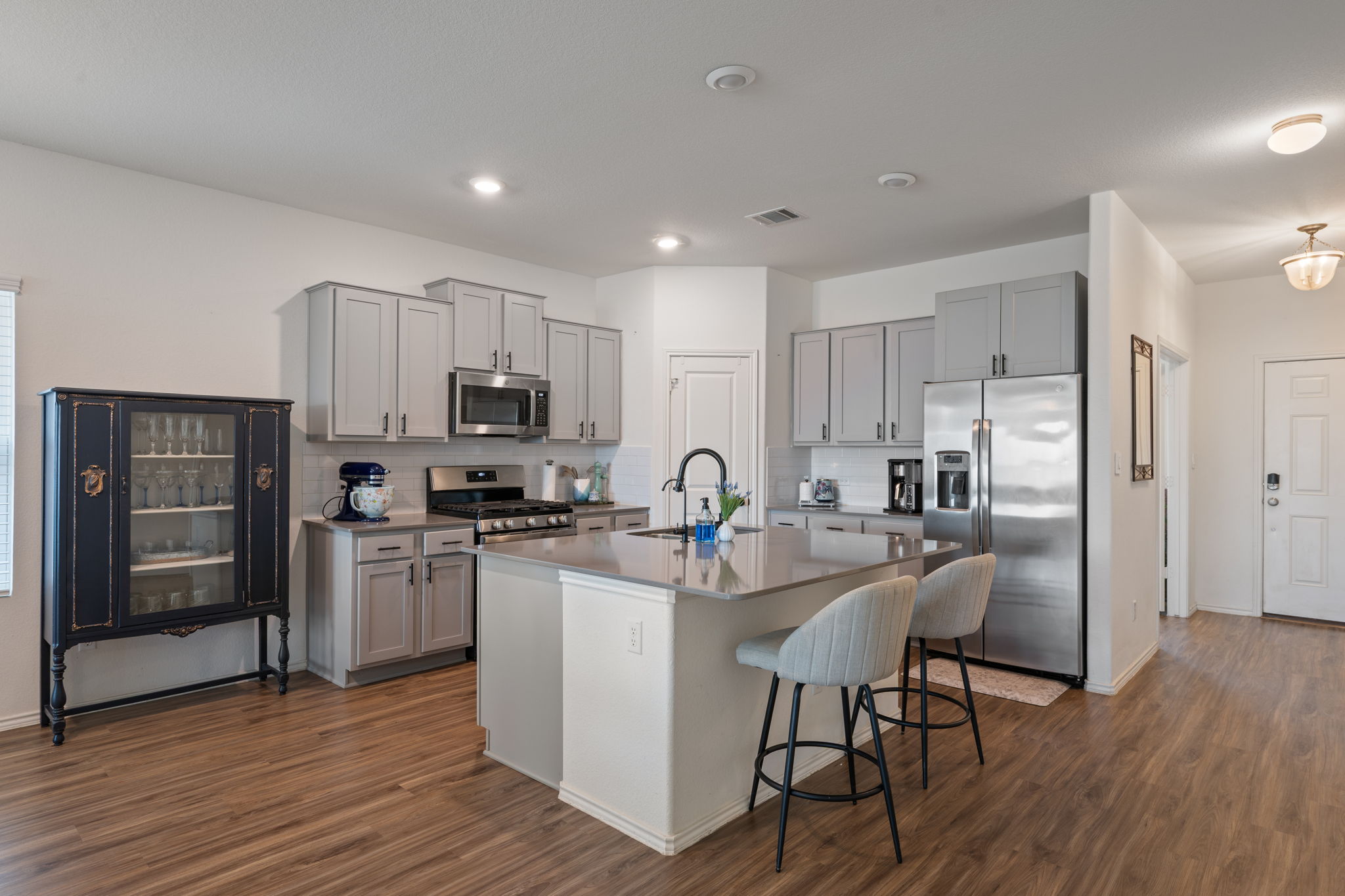 705 Mallow Road Leander, TX 78641 - Photo 7 of 29 a kitchen with stainless steel appliances granite countertop a refrigerator a stove top oven a sink dishwasher and white cabinets with wooden floor