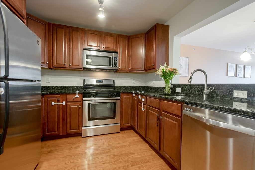 11 Cheriton Road, Unit 307 Boston, MA 02132 - Photo 1 of 12 a kitchen with kitchen island granite countertop wooden cabinets stainless steel appliances and a sink