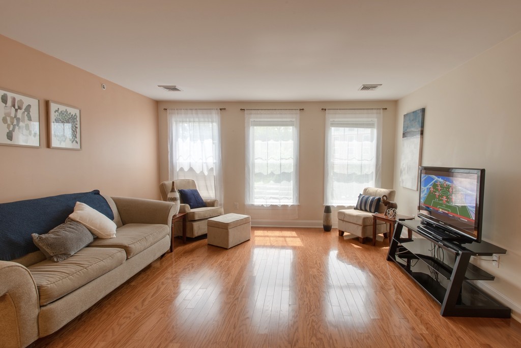 11 Cheriton Road, Unit 307 Boston, MA 02132 - Photo 4 of 12 a living room with furniture and a flat screen tv with wooden floor
