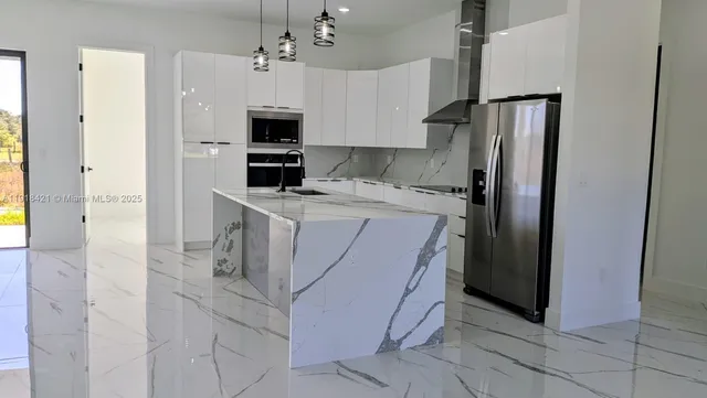 a kitchen with stainless steel appliances granite countertop a refrigerator and a stove top oven