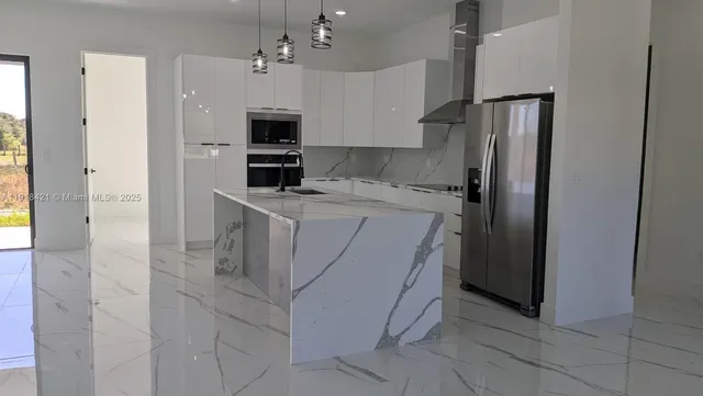 a large kitchen with stainless steel appliances kitchen island granite countertop a refrigerator a sink a stove and white cabinets