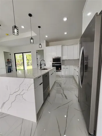 a large kitchen with stainless steel appliances kitchen island granite countertop a sink and cabinets