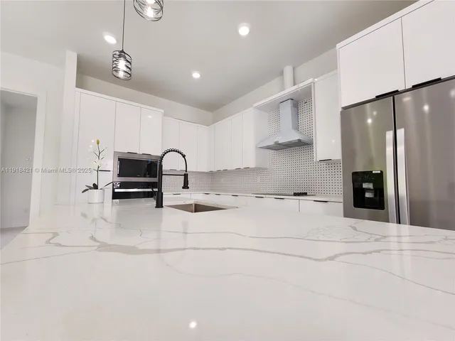 a view of open kitchen with kitchen island stainless steel appliances refrigerator oven dining table and chairs
