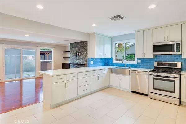 a large kitchen with stainless steel appliances granite countertop a stove a sink and a microwave