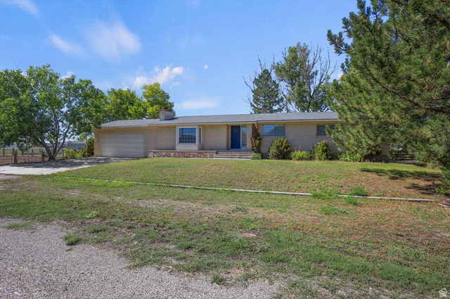 15295 North 5400th Street West Riverside, UT 84334 - Photo 43 of 54 Brick exterior, attached garage, prominent front door, mature trees, and landscaping