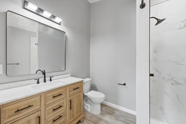 a bathroom with a granite countertop sink toilet a large mirror a vanity and shower