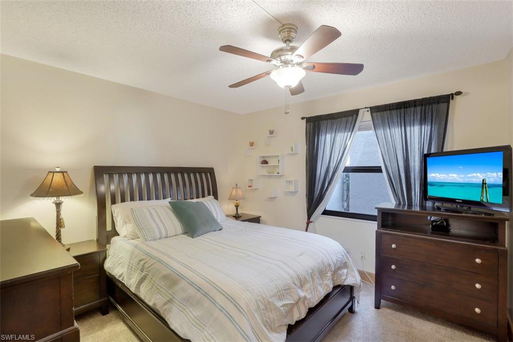 1782 Imperial Golf Course Boulevard, Unit C104 Naples, FL 34110 - Photo 18 of 34 a bedroom with a bed and a flat tv screen on dresser