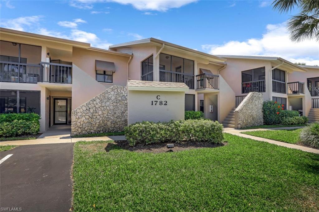1782 Imperial Golf Course Boulevard, Unit C104 Naples, FL 34110 - Photo 2 of 34 a front view of a house with a garden