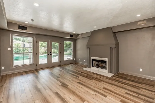 a view of an empty room with wooden floor fireplace and a window