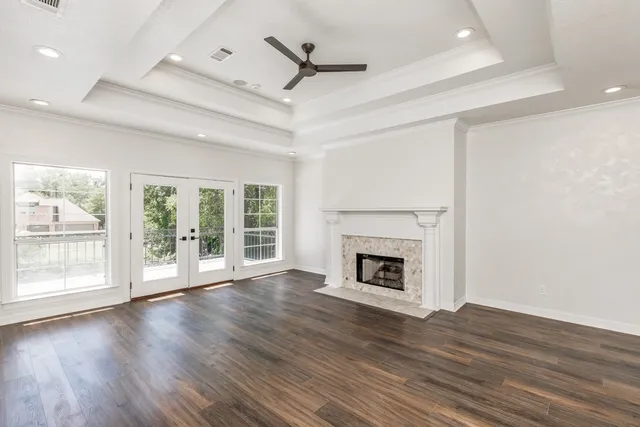 a view of an empty room with wooden floor fireplace and a window