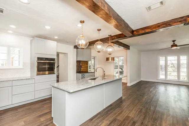 a large white kitchen with a large window a sink and a counter top space