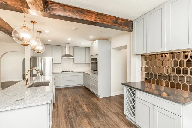 a kitchen with stainless steel appliances granite countertop a sink a stove and a wooden floors