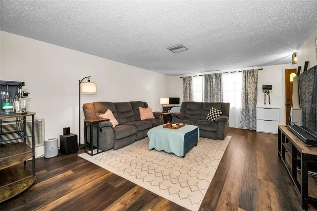 a living room with furniture a flat screen tv and a refrigerator