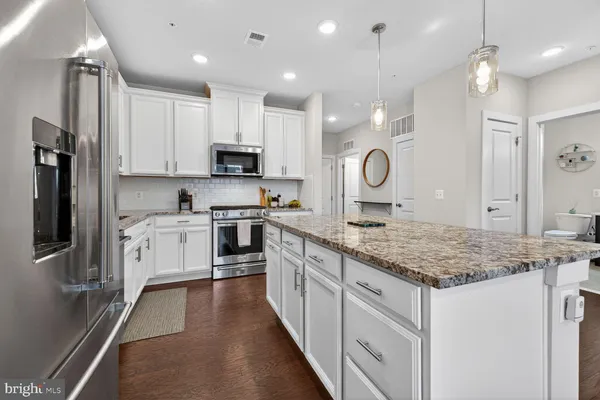 a kitchen with kitchen island granite countertop a sink a counter top space stainless steel appliances and cabinets