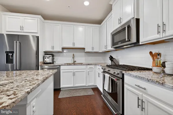 a kitchen with stainless steel appliances granite countertop a sink stove and microwave