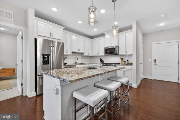 a kitchen with stainless steel appliances granite countertop a refrigerator a stove a sink a dining table and chairs with wooden floor