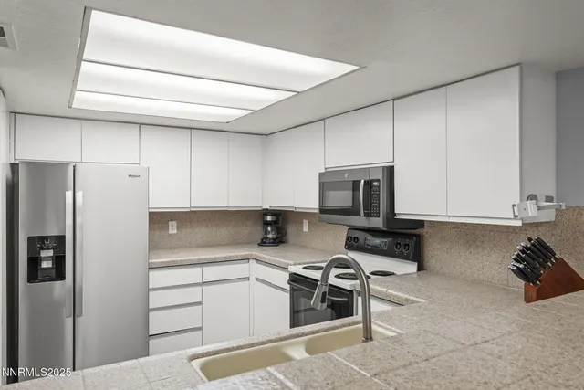 a kitchen with stainless steel appliances a stove a sink and a refrigerator