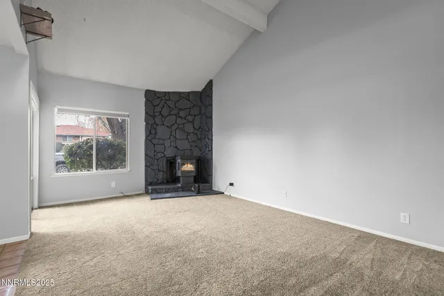 a view of an empty room with a fireplace and a window