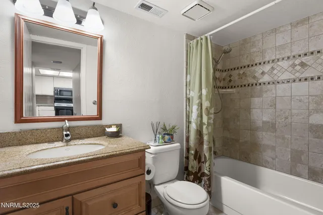 a bathroom with a granite countertop sink a toilet a mirror and shower