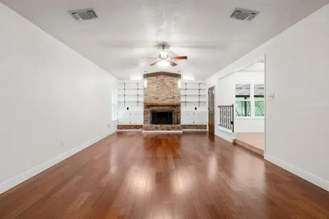 an empty room with wooden floor fireplace and fan