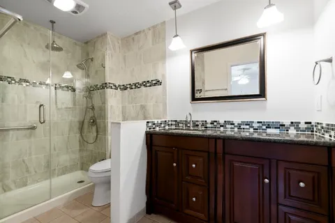 a bathroom with a double vanity sink toilet mirror and shower