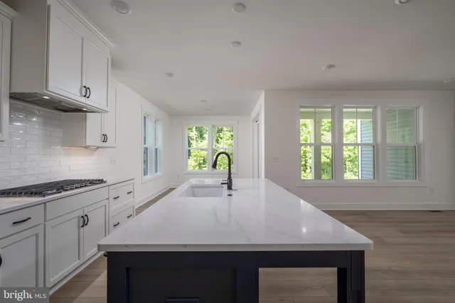 a kitchen with granite countertop a stove a sink and white cabinets