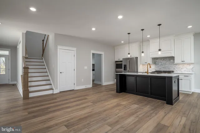 a kitchen with stainless steel appliances kitchen island granite countertop a wooden floors and white cabinets