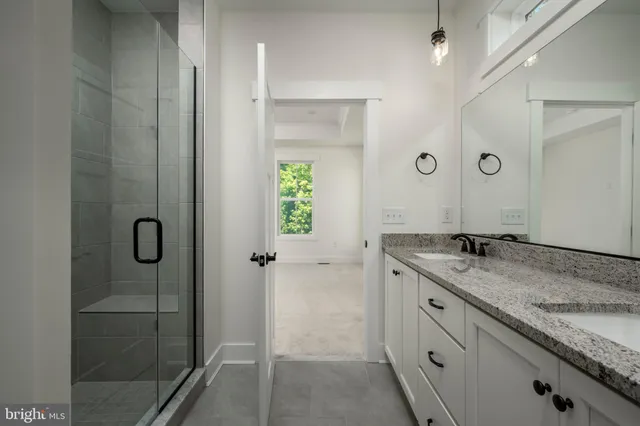 a bathroom with a granite countertop sink a mirror and shower