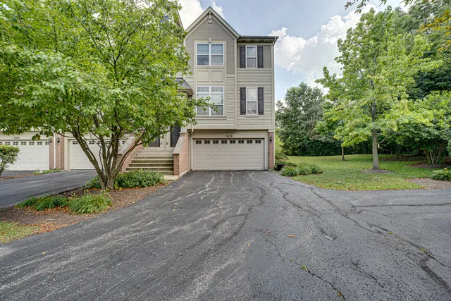 a view of a house with a yard and a large tree