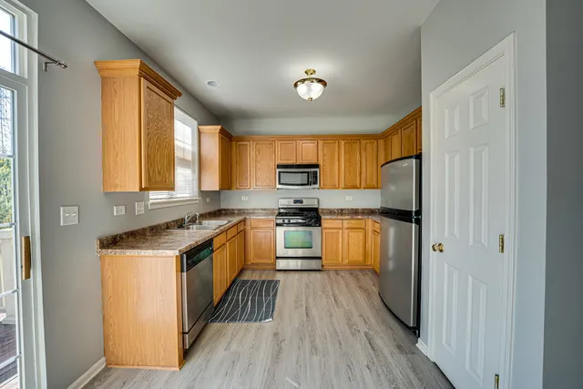 a kitchen with stainless steel appliances granite countertop refrigerator a stove top oven a sink and dishwasher with wooden floor