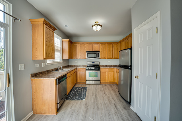 3379 Kentshire Circle, Unit 3379 Aurora, IL 60504 - Photo 7 of 17 a kitchen with stainless steel appliances granite countertop refrigerator a stove top oven a sink and dishwasher with wooden floor