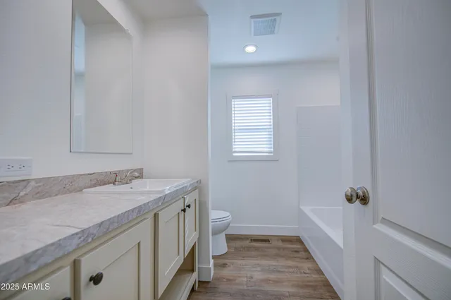 a bathroom with a granite countertop sink a toilet and shower