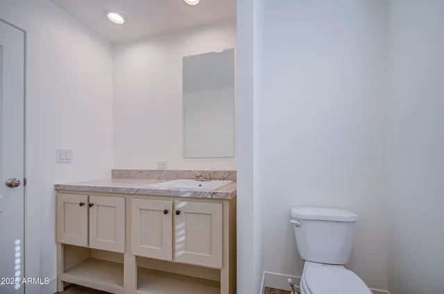 a bathroom with a granite countertop toilet and a sink