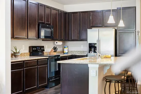 a kitchen with stainless steel appliances granite countertop a refrigerator a sink a stove and island