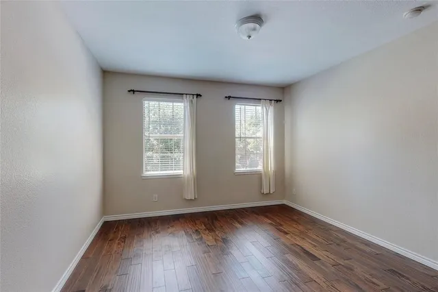 an empty room with wooden floor and window