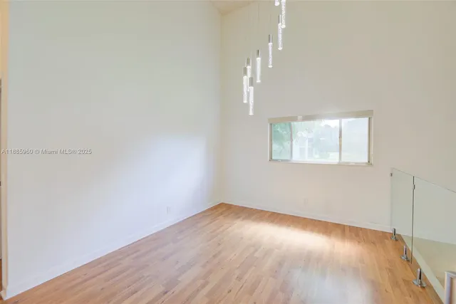 an empty room with wooden floor cabinet and windows