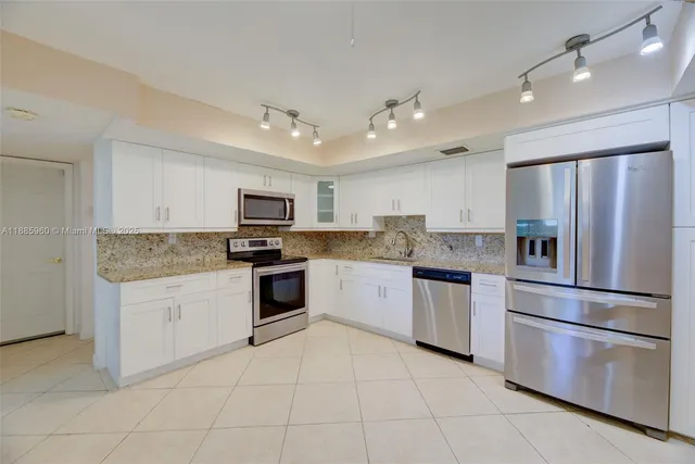 a kitchen with granite countertop stainless steel appliances and white cabinets