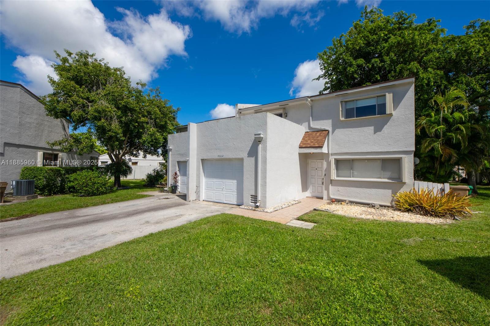 8662 Bridle Path Court, Unit 115A Davie, FL 33328 - Photo 2 of 50 a view of a white house with a yard and a large tree