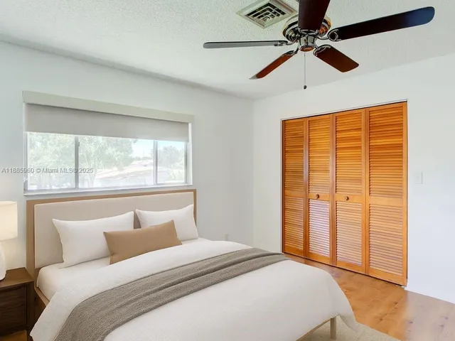 a bedroom with a large bed and a chandelier fan